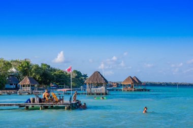 Quintana Roo, Mexico, May, 29, 2018: Unidentified people enjoying from a wooden pier and houses the Laguna Bacalar, Chetumal, Quintana Roo clipart