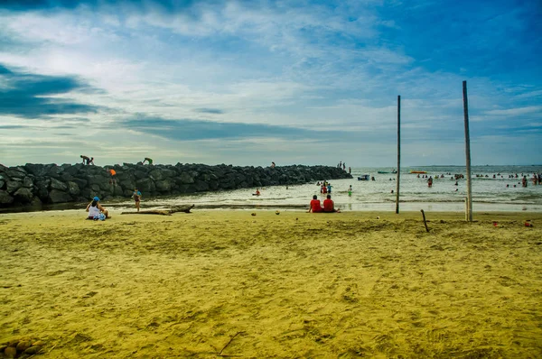 MANABI, ECUADOR - MAY 29, 2018: Unidentified tourists enjoying the beautiful natural landscape of Cojimies beach, while some teenagers are climbing a rock to jump into the water in Manabi — Stock Photo, Image