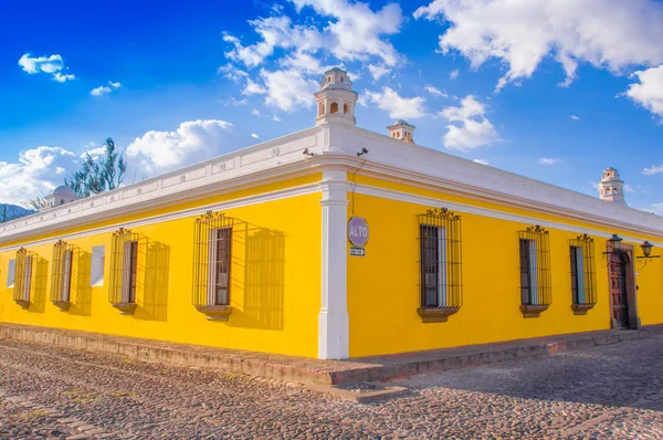 Ciudad de Guatemala, Guatemala, 25 de abril de 2018: Vista al aire libre de la perspectiva de esquina de una casa colonial de color amarillo brillante con ventanas con rejas en la ciudad de Antigua —  Fotos de Stock