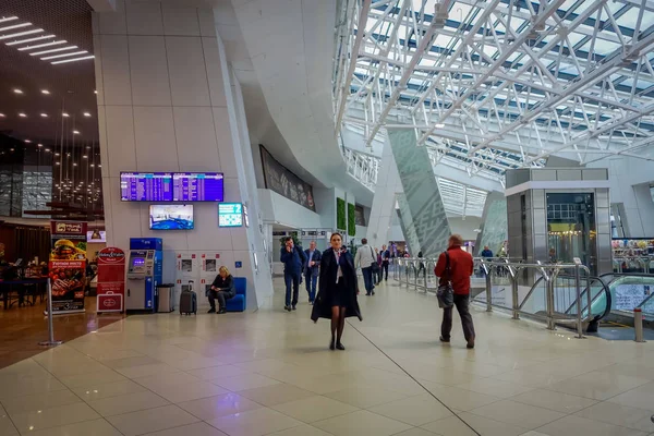 Minsk, Weißrussland - 01. Mai 2018: Unbekannte Touristen gehen mit ihrem Gepäck spazieren und beobachten einen Abflugschirm, der sich im Inneren des Flughafens von Minsk befindet — Stockfoto