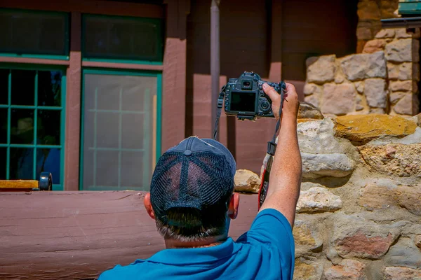 BRYCE CANYON, UTAH, JUNE, 07, 2018: Man wearing a black hat and blue shirt stretching the arm to take a picture of a beautiful golden-mantled ground squirrel in Bryce Canyon National Park, Utah — Stock Photo, Image
