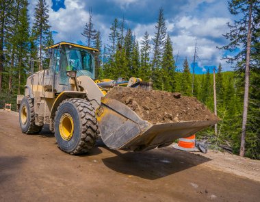 Yellowstone Milli Parkı, Wyoming, Amerika Birleşik Devletleri - 07 Haziran 2018: Açık bir yol inşaat muhteşem bir gün boyunca toprak kaldırma kamyon görünümünü. Yol çalışması Yellowstone Milli Parkı'nda
