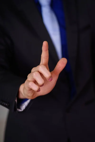 Close up de homem vestindo um terno, com uma mão aberta apontando na frente dele, em um fundo embaçado — Fotografia de Stock