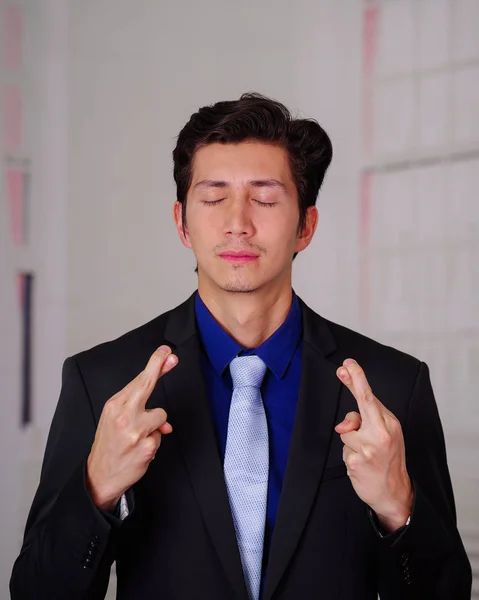 Close up of businessman wearing a suit, and crossing his fingers to get lucky, in a blurred background — Stock Photo, Image