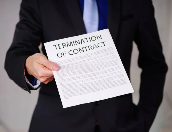 Bijgesneden afbeelding van zakenman dragen een pak en houden van een vel papier krijgen van de baas, met beëindiging van de tekst van de overeenkomst, in een onscherpe achtergrond — Stockfoto