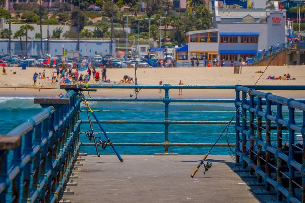 Vista al aire libre de las cañas de pescar de pie en un muelle de madera utilizado para las personas que suelen pescar en el muelle de Santa Mónica — Foto de Stock