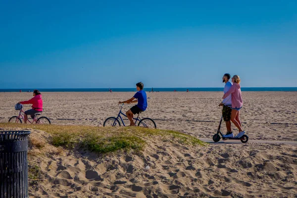 Los Angeles, Kalifornie, Usa, 15 června 2018: Neznámí lidé, cykloturistika a pár v skútr ve Venice Beach v Santa Monica, je populární domácí obyvatelé pro relax — Stock fotografie