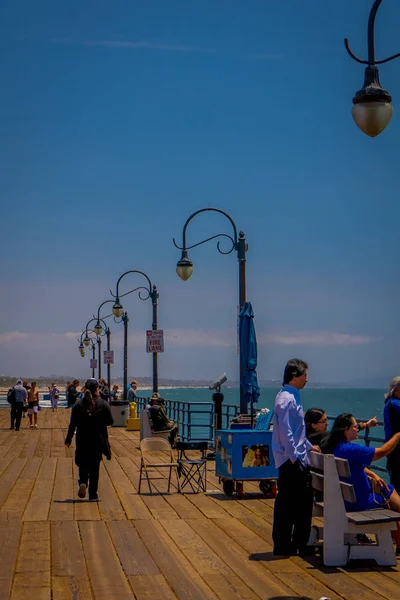 Los Angeles, California, Amerika Serikat, JUNE, 15, 2018: Orang-orang tak dikenal duduk di kursi bangku kayu di jembatan mengawasi Pantai Santa Monica di California Amerika Serikat selama hari yang cerah — Stok Foto