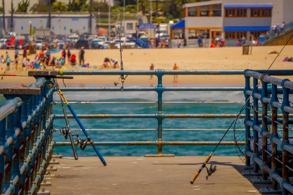 Vista al aire libre de las cañas de pescar de pie en un muelle de madera utilizado para las personas que suelen pescar en el muelle de Santa Mónica —  Fotos de Stock