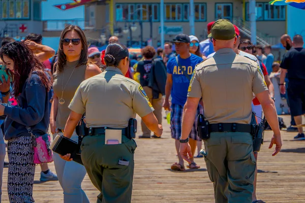 Los Ángeles, California, Estados Unidos, 15 de junio de 2018: Vista al aire libre de personas y policías caminando por el muelle con el final de la Ruta 66 en Santa Mónica. El parque de atracciones es una atracción turística de fama mundial — Foto de Stock