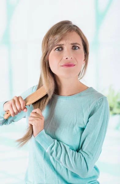 Primer plano de una hermosa mujer joven cepillándose el pelo en un fondo borroso —  Fotos de Stock