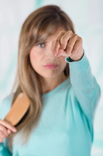 Primer plano del enfoque selectivo de la mujer señalando la mano frente a ella el pelo perdido durante el cepillado en un fondo borroso — Foto de Stock