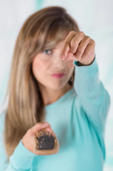 Close up of selective focus of woman pointing the hand in front of her the lost hair during brushing in a blurred background — Stock Photo, Image