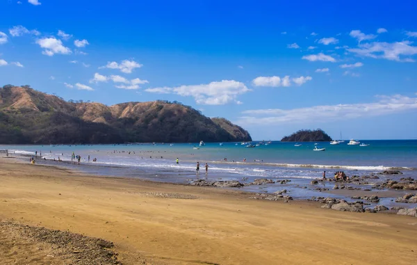 Outdoor view of unidentified people in the beach taking the sun and enjoying the beautiful landscape of Coconut on an exotic beach with palm tree and blue sky — Stock Photo, Image