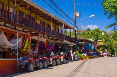 Montezuma, Costa Rica - June 28, 2018: Beautiful view of Montezuma town surrounding of tourists, buildings and and cars parked in the street in gorgeus sunny day in Costa Rica clipart