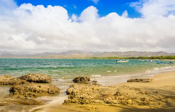 Bella vista esterna della spiaggia rocciosa di Montezuma, in splendida giornata di sole e acqua turchese e cielo blu con alcune nuvole e molte barche in acqua — Foto Stock