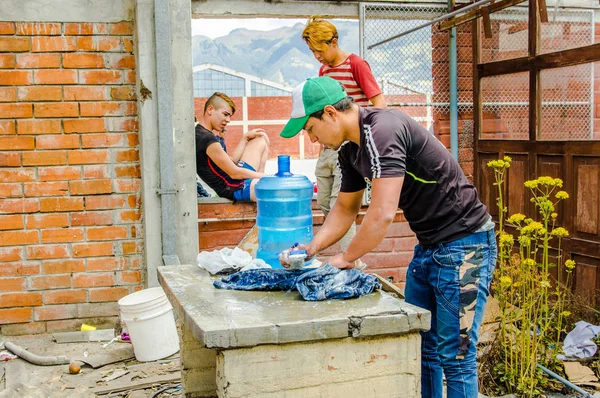 Quito, Ekvádor, 21 srpna 2018: Venkovní pohled neznámí mladí kluci praní oblečení uvnitř útočiště pro venezuelské lidí, že uniknout z jejich země kvůli ekonomické situaci — Stock fotografie