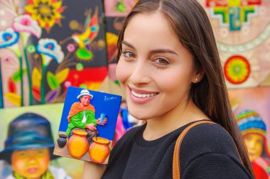 Smiling woman holding a souvenir in a shopstore in Banos, Ecuador. Banos is a small touristy town, which is mainly known for its various outdoor acitivities clipart