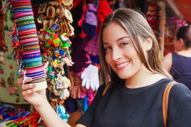 Turist küçük kasabada Banos bir Hatıra Eşyası alanda dokuma bir bilezik arıyorsunuz bir shopstore güzel gülümseyen genç kadın