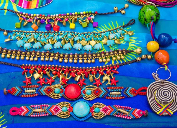 Samara, Costa Rica, 26 de junio de 2018: Primer plano de hermosas y coloridas artesanías en una tienda callejera sobre un fondo de tela azul en la playa de Samara —  Fotos de Stock
