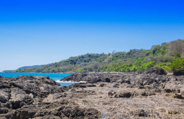 Prachtige landschap van de rotsachtige strand en bomen in Playa Montezuma in prachtige blauwe lucht en zonnige dag — Stockfoto