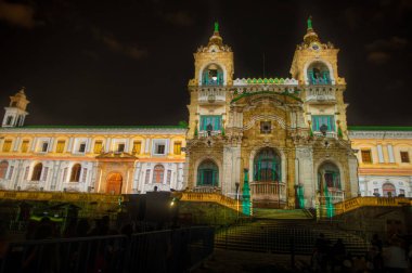 QUITO, ECUADOR- AUGUST, 15, 2018: Crowd admiring the spectacle of lights projected on the facade of San francisco church, illuminated with laser technology in festival of light every August in Quito clipart