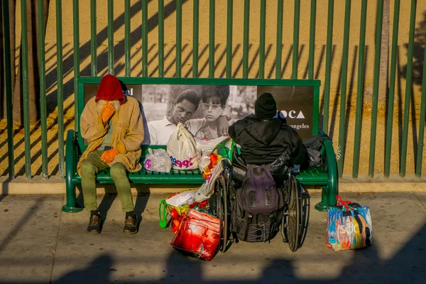 Los Angeles, Califórnia, EUA, 20 de agosto de 2018: Vista ao ar livre do casal de desabrigados em um banco de parque, mulher em uma cadeira de rodas em Los Angeles, Califórnia — Fotografia de Stock