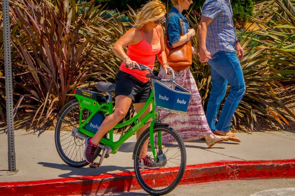 Los Angeles, California, Estados Unidos, 15 de junio de 2018: Mujer no identificada en bicicleta verde y pareja caminando a su lado en las calles de Venice Beach en Santa Monica — Foto de Stock