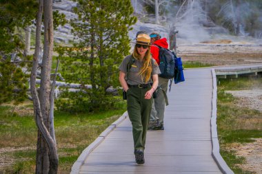 Yellowstone, Montana, 24 Mayıs 2018: Açık bakış tanımlanamayan turist eski sadık üst şofben havzasında ahşap yol üzerinde bir kadın park korucusu ile konuşmak