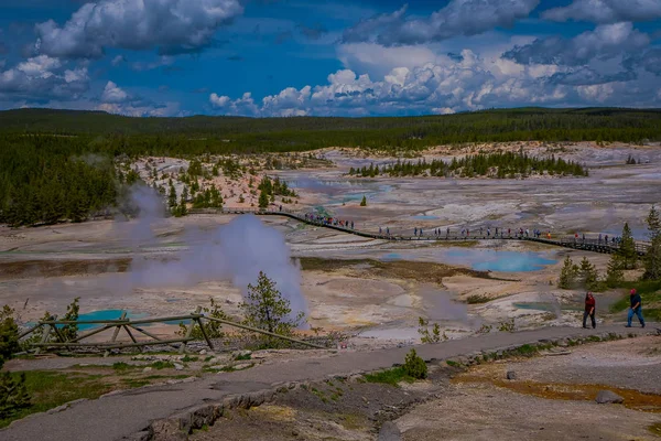 YELLOWSTONE, MONTANA, USA 24 DE MAYO DE 2018: Vista superior de personas caminando en el paseo marítimo entre piscinas y géiseres, cuenca de porcelana de Norris Geyser Basin, Parque Nacional de Yellowstone, Wyoming — Foto de Stock