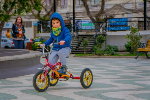 Valparaiso, Şili - Eylül, 15, 2018: Açık görünüm soğuk hava için mavi ceket giyiyor ve onun tricyle dowtown Valparaiso üzerinde bulunan bir park Meydanı'nda Binicilik tanımlanamayan küçük çocuk — Stok fotoğraf