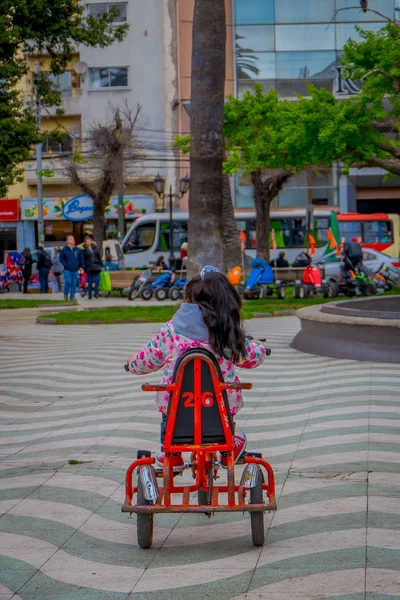 Valparaiso, Şili - Eylül, 15, 2018: Açık kimliği belirsiz küçük kız onun tricyle dowtown Valparaiso üzerinde bulunan bir park Meydanı'nda tesisi görünümünü — Stok fotoğraf