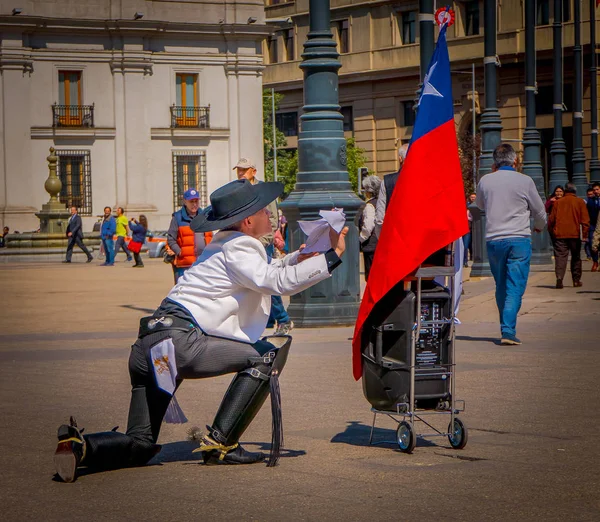 SANTIAGO, CHILE - SETEMBRO 13, 2018: Vista ao ar livre de homem não identificado vestindo botas, camiseta branca e calças pretas oh seus joelhos na praça Armas em frente a uma bandeira chilena em Santiago, Chile — Fotografia de Stock