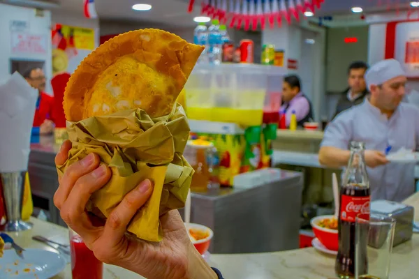 SANTIAGO, CHILE - SETEMBRO 13, 2018: Fechar o foco seletivo de uma mão de homem com uma Empanada chilena, massa assada recheada com presunto e queijo — Fotografia de Stock
