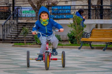 Valparaiso, Şili - Eylül, 15, 2018: Açık görünüm soğuk hava için mavi ceket giyiyor ve onun tricyle dowtown Valparaiso üzerinde bulunan bir park Meydanı'nda Binicilik tanımlanamayan küçük çocuk
