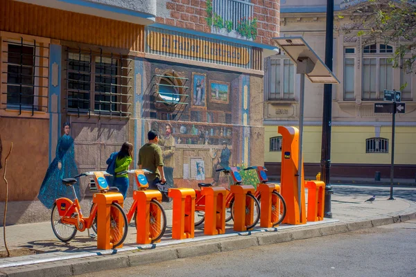 Santiago, chile - 13. September 2018: Unbekannte gehen auf dem Bürgersteig in der Nähe orangefarbener Fahrräder, die in einer Reihe im Zentrum der Stadt in santiago, chile geparkt sind — Stockfoto