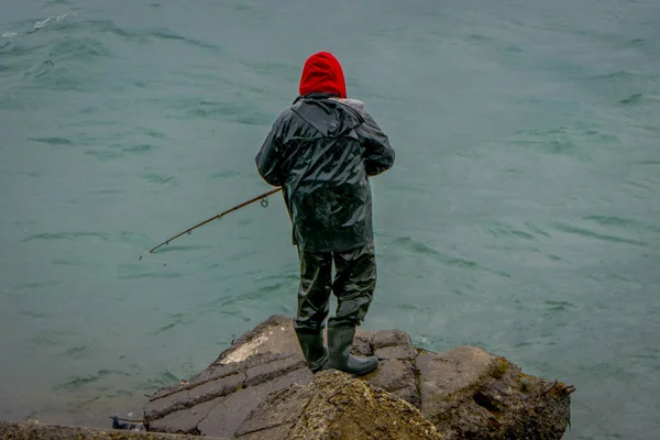 Pescador no identificado parado en una roca con caña de pescar en patagonia chilena — Foto de Stock