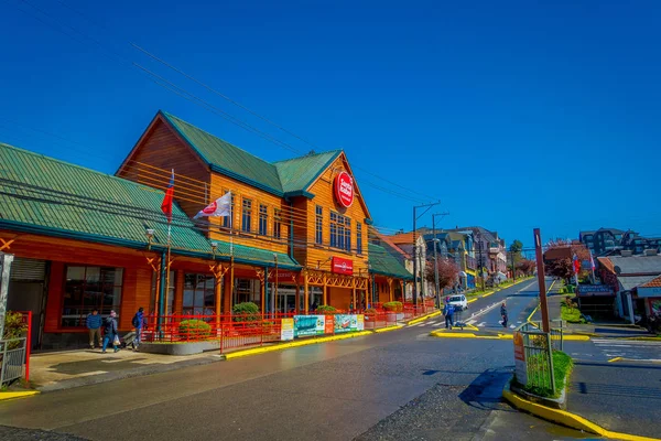 Puerto varas, chile, 23. september 2018: aussenansicht eines schönen hölzernen gebäudes an der ecke mit ein paar autos, die an einem sonnigen tag mit blauem himmelhintergrund in puerto varas in chile unterwegs sind — Stockfoto