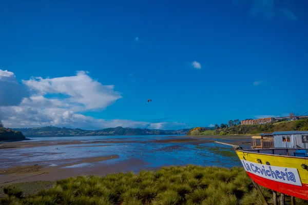 CHILOE, CHILE - SEPTEMBER, 27, 2018: View of beautiful colorful wooden restaurant cebiche on stilts palafitos, in a low tide day wooden house of yellow and red color at sunny day in Castro, Chiloe — Stock Photo, Image