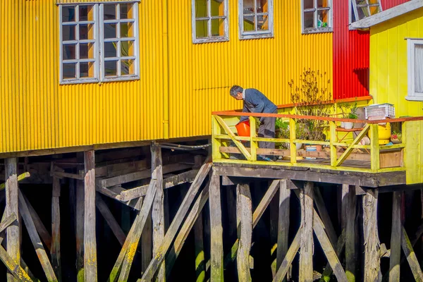 Homem não identificado em sua casa amarela em palafitos palafitos em Castro, Chiloe Island, Patagônia — Fotografia de Stock