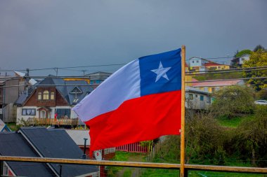Güzel ve renkli ile sallayarak Şili bayrağı açık görünüm stilts üzerinde arkasında palafitos Castro, Chiloe Adası horizont içinde evler.