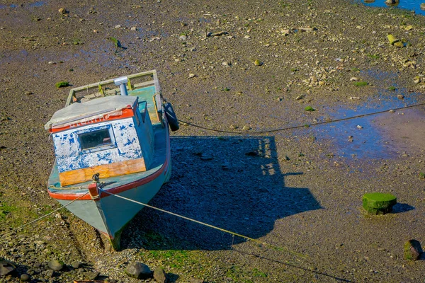 Vista al aire libre de un solo barco en una marea baja dejado atrás con algunas cuerdas de seguridad en Castro, Isla de Chiloé, Patagonia —  Fotos de Stock