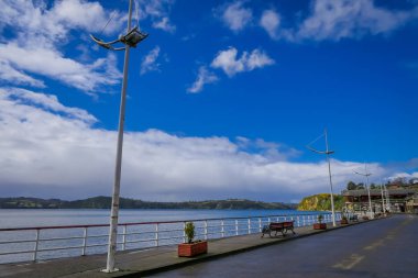 Chiloe, Şili - Eylül, 27, 2018: Bazı otomobillerin açık görünüm Chiloe Şili'deki güzel ahşap evlerin islandm çevreleyen muhteşem chonchi Limanı önünde sokakta park edilmiş