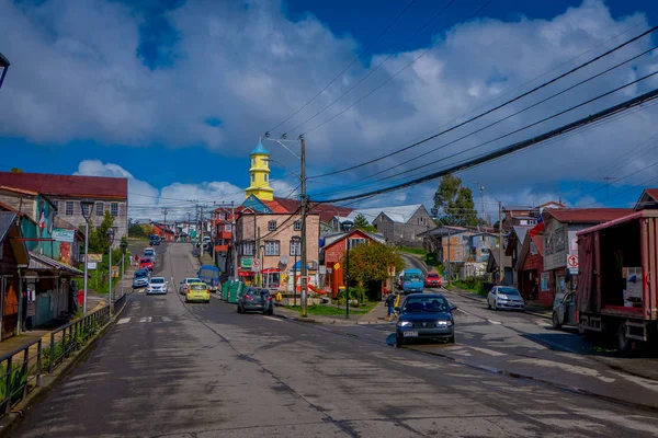 CHILOE, CHILE - SEPTEMBER, 27, 2018: Outdoor view of some cars parking at one side of the road cose to many wooden buildings in Chiloe island in a gorgeous blue sky in Chile — Stock Photo, Image