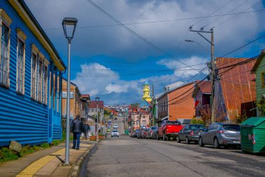 Chiloe, Şili - Eylül, 27, 2018: Şili'deki muhteşem mavi gökyüzünde Chiloe adasında birçok ahşap binalar için yol cose bir tarafındaki otopark bazı otomobillerin açık görünüm