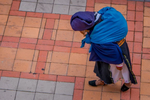 COTACACHI, ECUADOR, 06 DE NOVIEMBRE DE 2018: Vieja indígena caminando por las calles de la ciudad de Cotacachi usando un bastón y llevando una bolsa pesada en la espalda — Foto de Stock