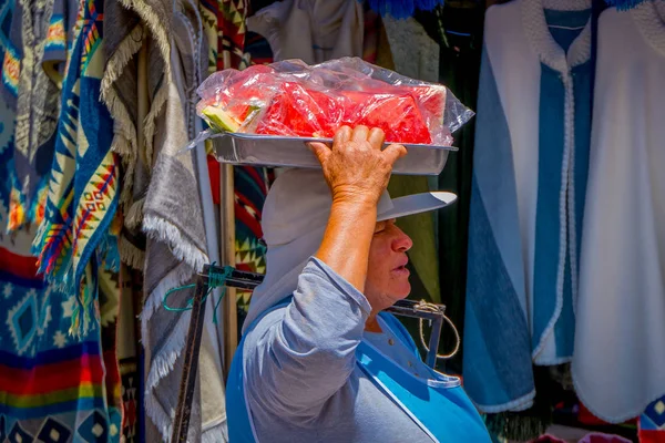 Otavalo, Ecuador, November 06, 2018: Buiten beeld van de vrouw in de straten van de stad van Otavalo, verkoop van segmenten van watermeloen in een metalen lade — Stockfoto