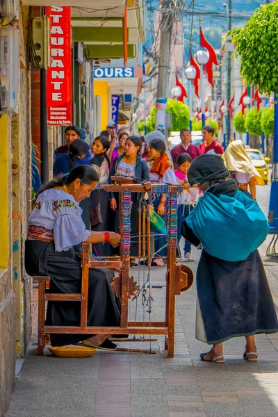 OTAVALO, ECUADOR, 06 DE NOVIEMBRE DE 2018: Mujer no identificada con una bolsa de turquesa y mirando el brazalete hecho a mano en la acera de la ciudad de Otavalo — Foto de Stock