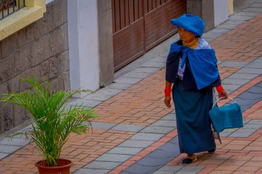 Cotacachi, Ekvator, 06 Kasım 2018: yerli giysi ve eşarp mavi giyen ve mavi bir çanta Cotacachi sokaklarında yürürken elinde tutan kimliği belirsiz bir kadın