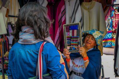 Otavalo, Ekvator, 06 Kasım 2018: müşteriler giysilerini Otavalo bir sokak pazarında kanıtlamak için bir ayna tutan İspanyol yerli kadın, kapat